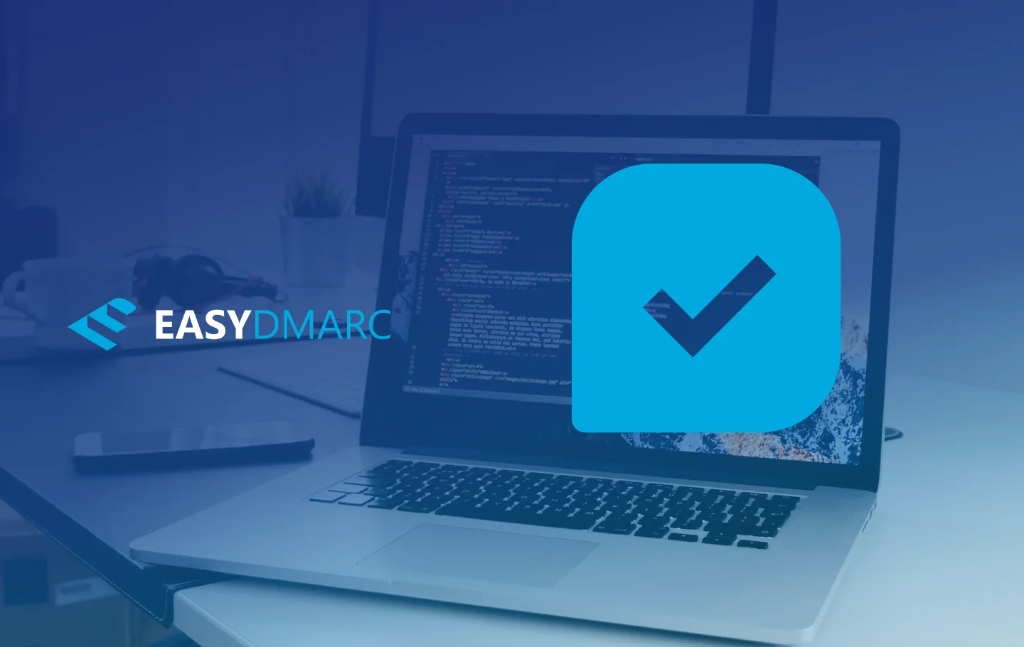 A laptop on a desk, a plant on it's left side, blue picture covered with the EasyDMARC logo