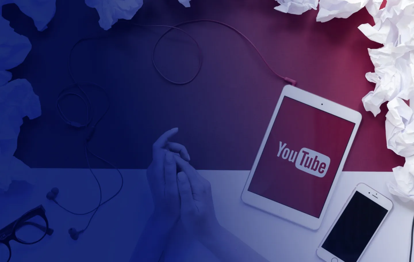 A person's hands on a table, an Ipad on the right side with YouTube logo on it